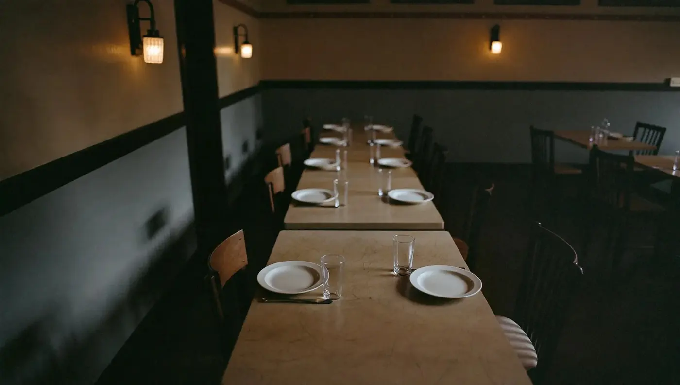 A long table set for several diners in a quiet dining room.